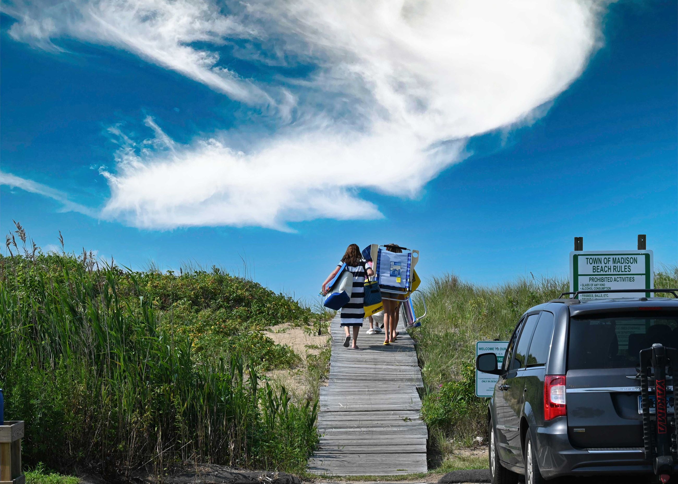 people walk along the boardwalk from the parking lot towards the beach at the  Surf Club